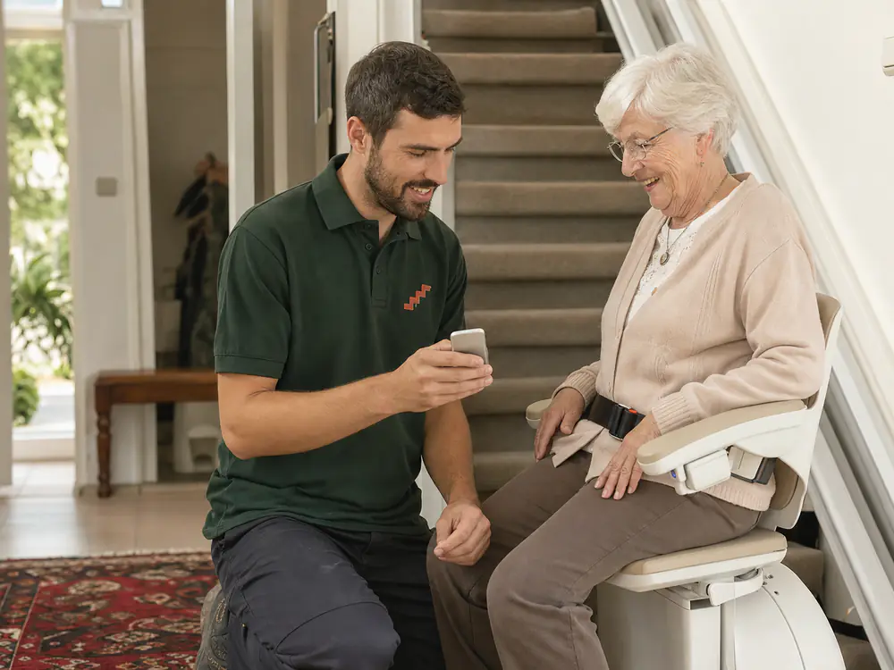 Monteur legt de afstandsbediening uit aan een bewoonster op haar nieuwe traplift