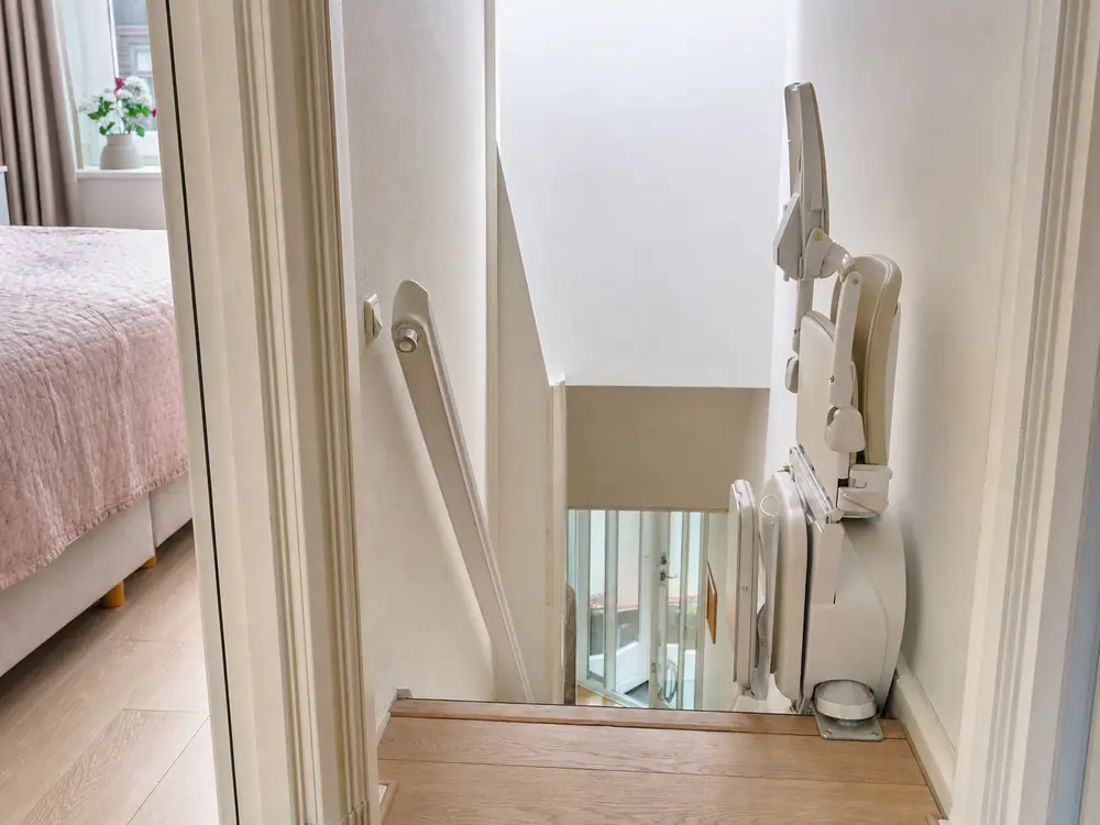 Smalle, steile trap met een opgeklapte traplift boven aan de trap