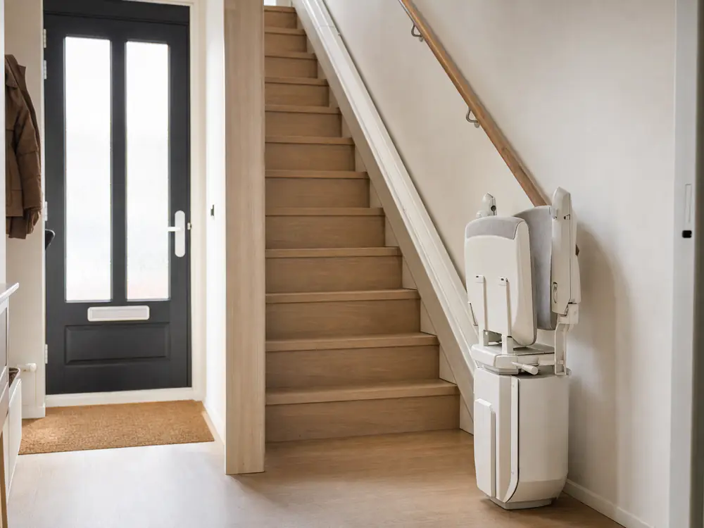 Traplift voor een rechte trap, zitting en voetplaat opgeklapt onderaan de trap